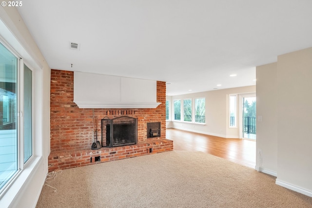 unfurnished living room with light colored carpet and a brick fireplace