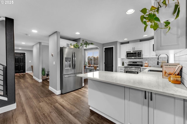 10417 NE 86th Ave, Vancouver, WA 98662 - kitchen featuring appliances with stainless steel finishes, a peninsula, decorative backsplash, light stone countertops, and white cabinetry