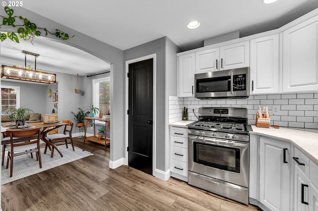 10417 NE 86th Ave, Vancouver, WA 98662 - kitchen featuring appliances with stainless steel finishes, arched walkways, decorative backsplash, light wood finished floors, and recessed lighting