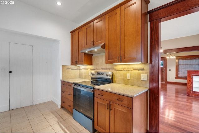 2309 7th St, Tillamook, OR 97141 - kitchen featuring stainless steel electric range, under cabinet range hood, tasteful backsplash, baseboards, and light stone counters
