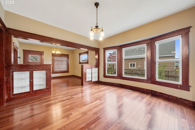 2309 7th St, Tillamook, OR 97141 - unfurnished living room featuring a chandelier, baseboards, light wood-type flooring, and plenty of natural light