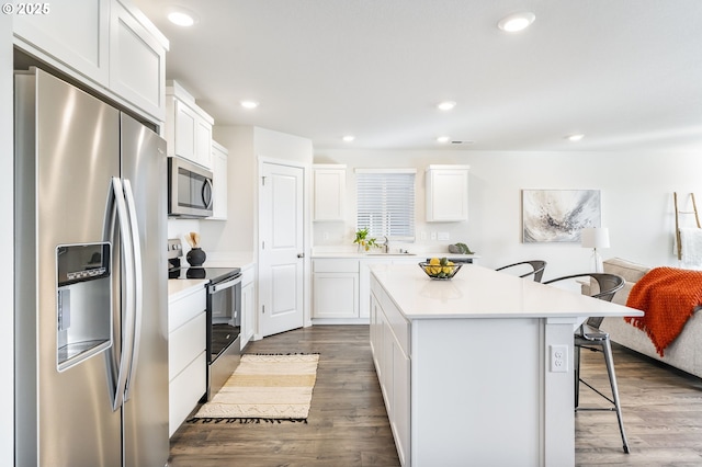 kitchen featuring stainless steel appliances, a breakfast bar, dark wood finished floors, and a center island