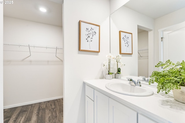 bathroom featuring a spacious closet, wood finished floors, vanity, and baseboards