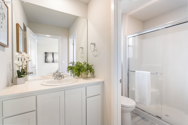 bathroom with a stall shower, vanity, and toilet