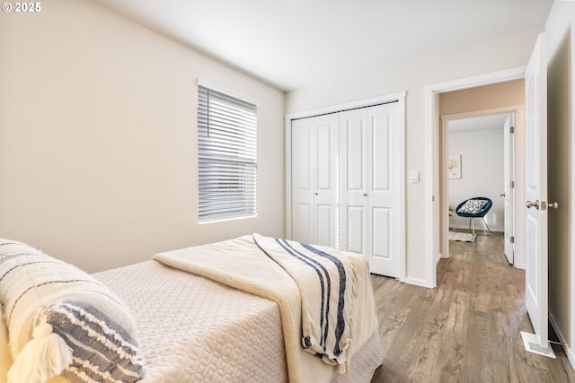 bedroom featuring a closet, wood finished floors, and baseboards