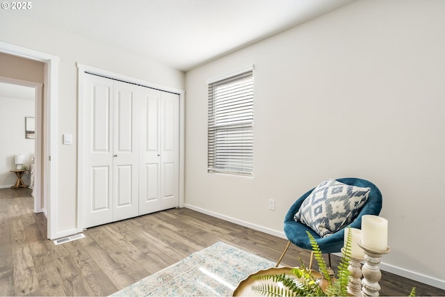 sitting room with wood finished floors, visible vents, and baseboards