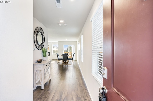 hallway with baseboards, visible vents, and dark wood-type flooring