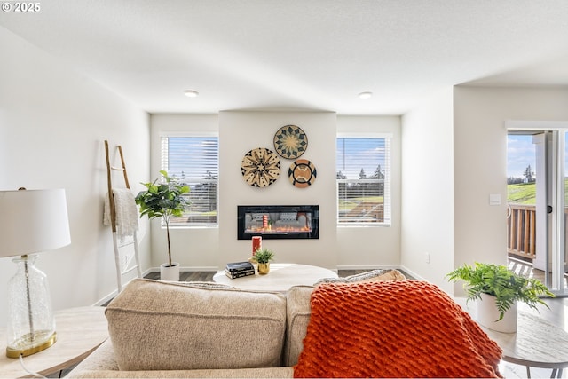 living room with plenty of natural light, baseboards, and a glass covered fireplace