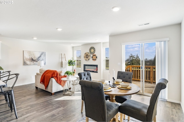 dining space with recessed lighting, visible vents, wood finished floors, and a glass covered fireplace