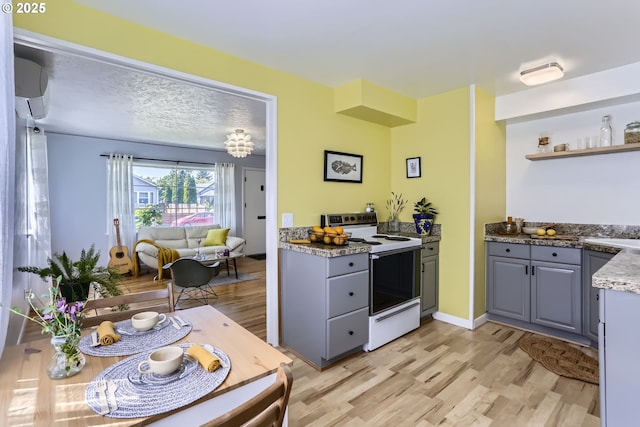 6540 SE 88th Ave, Portland, OR 97266 - kitchen with electric range, light wood-type flooring, gray cabinets, an AC wall unit, and open shelves