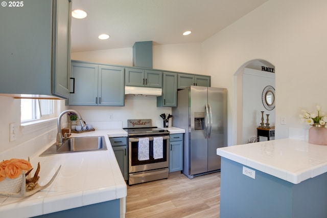 1185 Shady Ln, Keizer, OR 97303 - kitchen featuring stainless steel appliances, under cabinet range hood, tile countertops, lofted ceiling, and light wood-type flooring