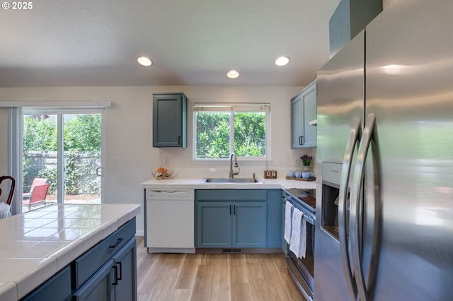 1185 Shady Ln, Keizer, OR 97303 - kitchen featuring appliances with stainless steel finishes, tile counters, recessed lighting, light wood-type flooring, and blue cabinets