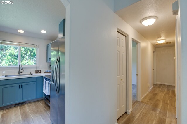 1185 Shady Ln, Keizer, OR 97303 - kitchen featuring blue cabinetry, light wood-style flooring, light countertops, appliances with stainless steel finishes, and a textured ceiling