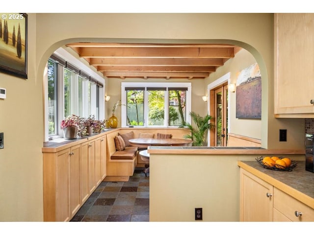 kitchen featuring light brown cabinetry, arched walkways, breakfast area, and beam ceiling