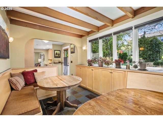 dining area with arched walkways and beamed ceiling