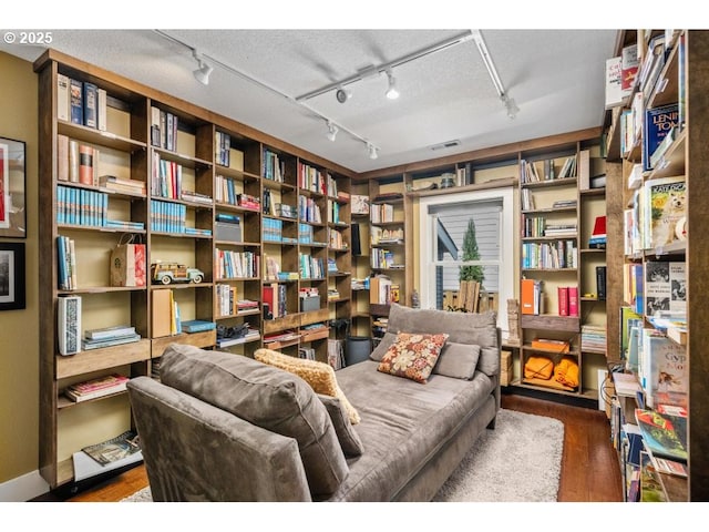 sitting room with track lighting, wood finished floors, and visible vents
