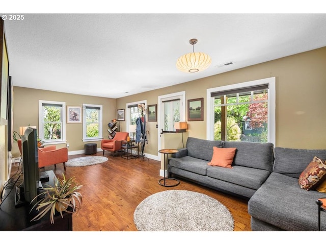 living area featuring visible vents, baseboards, wood finished floors, and a wealth of natural light
