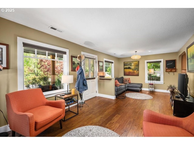 living room featuring baseboards, visible vents, a healthy amount of sunlight, and hardwood / wood-style flooring
