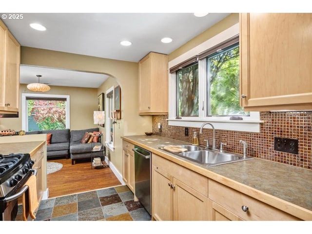 kitchen featuring stainless steel appliances, decorative backsplash, a sink, and light brown cabinets