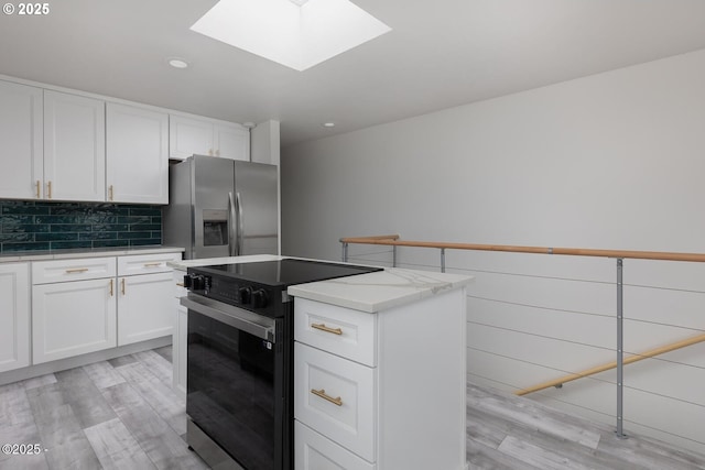 3929 NW Jetty Ave Unit 5, Lincoln City, OR 97367 - kitchen with range with electric cooktop, stainless steel fridge, a skylight, light wood finished floors, and white cabinets