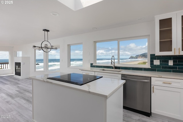 3929 NW Jetty Ave Unit 5, Lincoln City, OR 97367 - kitchen with stainless steel dishwasher, a sink, black electric cooktop, a kitchen island, and light stone countertops
