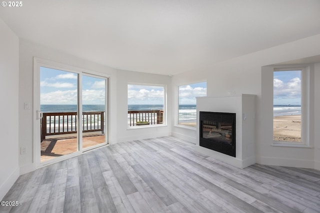 3929 NW Jetty Ave Unit 5, Lincoln City, OR 97367 - unfurnished living room featuring wood finished floors, a water view, a glass covered fireplace, and baseboards