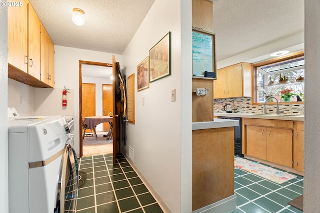 kitchen with a textured ceiling, washing machine and dryer, backsplash, black dishwasher, and sink