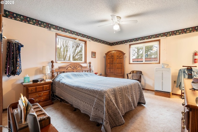 bedroom with a textured ceiling, ceiling fan, refrigerator, and carpet flooring