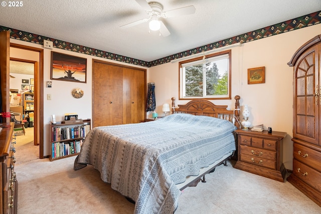 carpeted bedroom with a closet, a textured ceiling, and ceiling fan