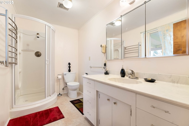 bathroom featuring tile patterned floors, toilet, vanity, and a shower with shower door