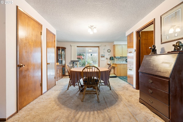 dining room featuring a textured ceiling and light colored carpet