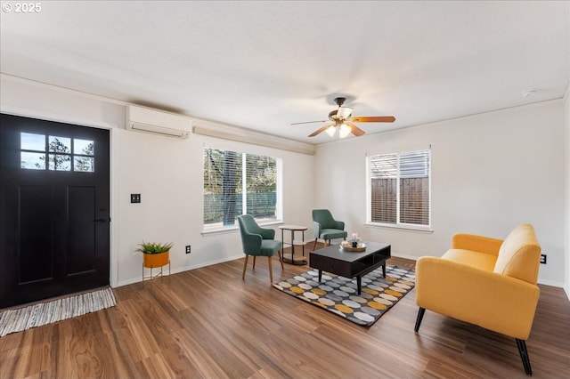 interior space with a ceiling fan, a wall mounted air conditioner, baseboards, and wood finished floors