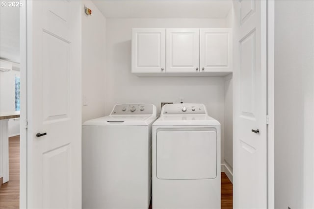 laundry room featuring washer and dryer, cabinet space, and wood finished floors