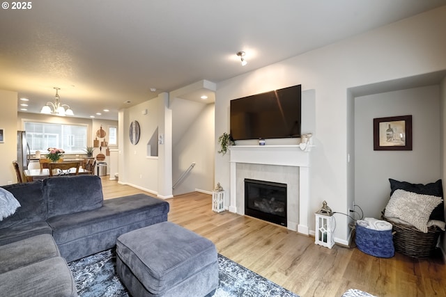living room featuring wood finished floors, a chandelier, recessed lighting, a tile fireplace, and baseboards
