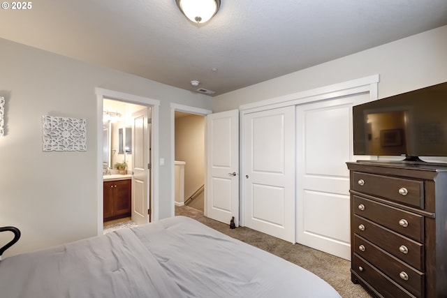 carpeted bedroom with a closet and ensuite bathroom