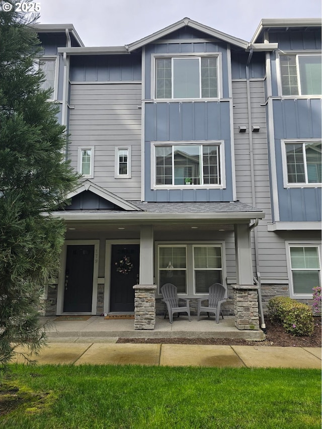 view of front of house featuring covered porch, board and batten siding, and stone siding