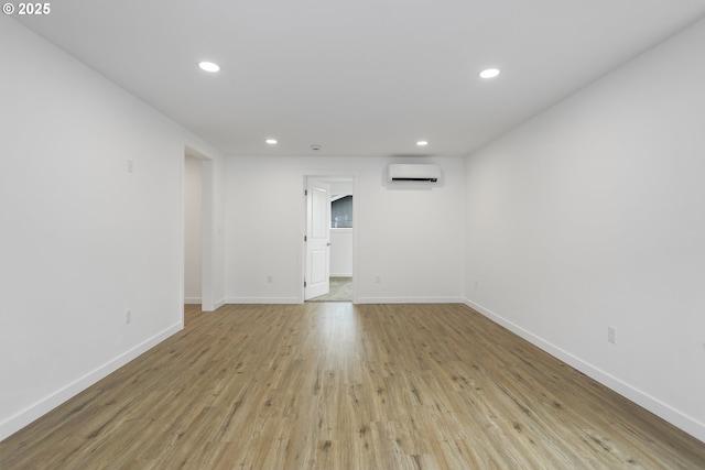 spare room with an AC wall unit, recessed lighting, wood finished floors, and baseboards