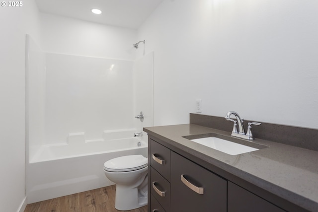 full bath featuring toilet, wood finished floors,  shower combination, vanity, and recessed lighting