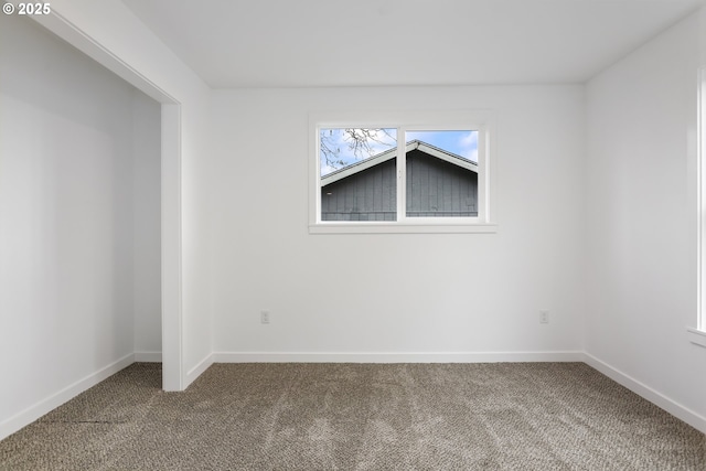 unfurnished room featuring dark carpet and baseboards