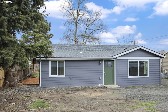 back of house featuring roof with shingles, fence, and a wooden deck