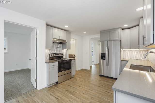 kitchen featuring light wood-style floors, appliances with stainless steel finishes, under cabinet range hood, a sink, and recessed lighting