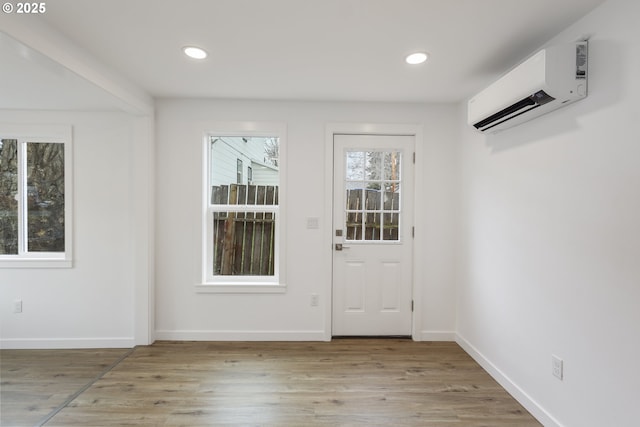 doorway to outside with recessed lighting, light wood-style flooring, and a wall mounted AC