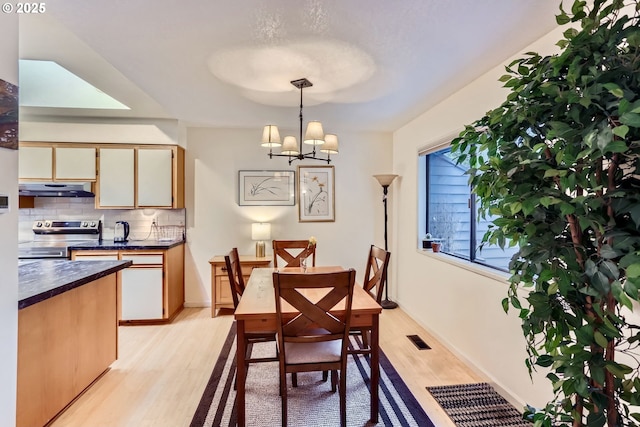 dining area with light hardwood / wood-style flooring and a notable chandelier