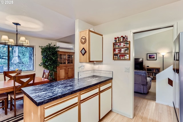 kitchen with white cabinets, hanging light fixtures, light hardwood / wood-style floors, kitchen peninsula, and a wall unit AC