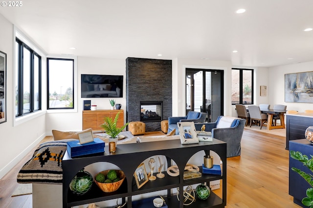 living area featuring light wood-type flooring, a wealth of natural light, and a multi sided fireplace