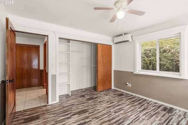 409 Pacific Ave, Brookings, OR 97415 - unfurnished bedroom with an AC wall unit, a closet, wood finished floors, baseboards, and ceiling fan