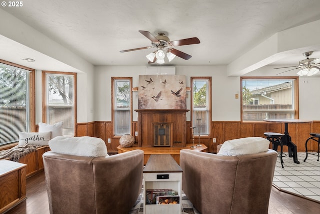 409 Pacific Ave, Brookings, OR 97415 - living room featuring a wainscoted wall, a ceiling fan, wooden walls, plenty of natural light, and a glass covered fireplace