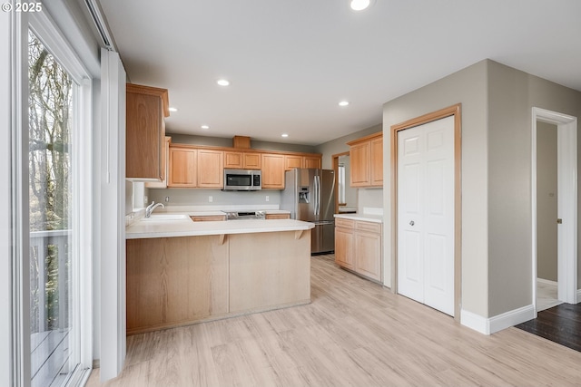 kitchen featuring sink, light hardwood / wood-style flooring, a breakfast bar, appliances with stainless steel finishes, and kitchen peninsula