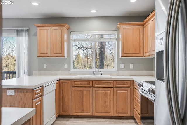 kitchen featuring sink, light hardwood / wood-style flooring, kitchen peninsula, and appliances with stainless steel finishes