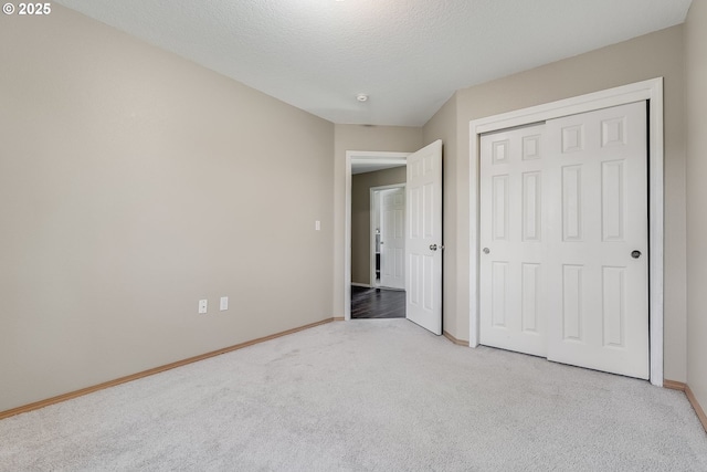 unfurnished bedroom with light carpet, a closet, and a textured ceiling